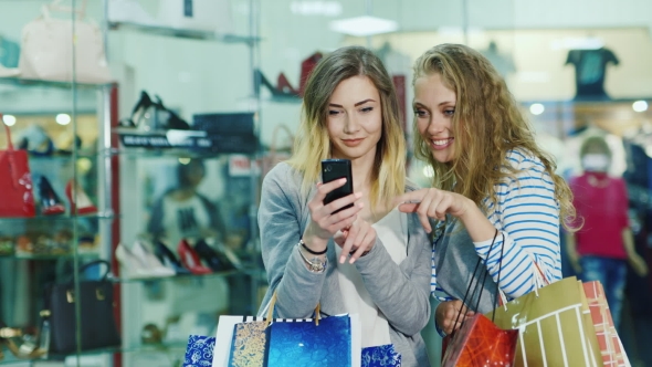 Two Attractive Woman Looking At The Photos On The Phone