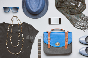 r, stylish handbag, smartphone, black top glamor shoes trendy necklace blue hat and sunglasses.Urban summer outfit. Overhead, top view gray background