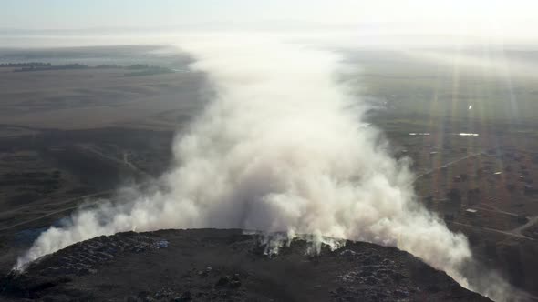 Aerial view of smoke from burning garbage pile in landfill, Earth pollution concept