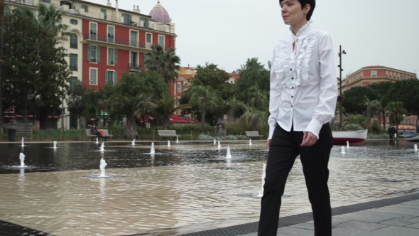 Tourist Young Woman Walking Along Fountain In Nice. 