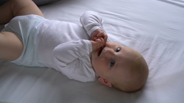 Mother Tickles The Baby And He Laughs Lying On The Bed