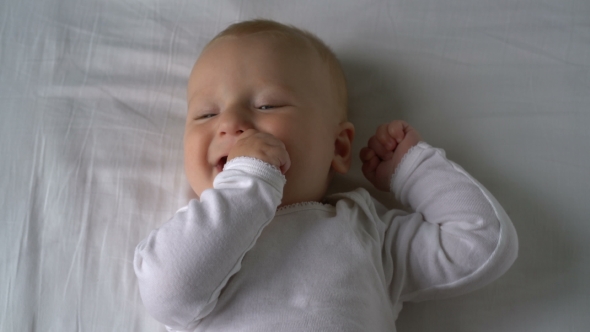 Mother Tickles The Baby And He Laughs Lying On The Bed