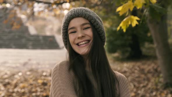 Carefree Teen Laughing and Poses at Camera in Autumn Park