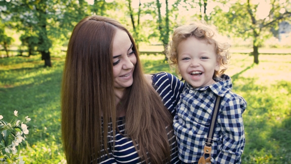 Cheerful Mum And Son Frolic In a Summer Garden