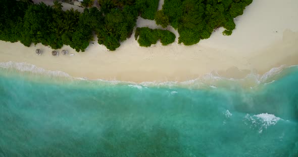 Beautiful fly over tourism shot of a sandy white paradise beach and aqua turquoise water background 