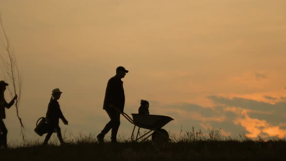 Young Family Having Fun Outdoors in Their Farm. Silhouette Family of Four Planting a New Tree at