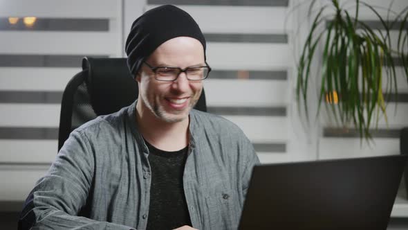 A Man Communicates with Colleagues or Friends Using the Internet and a Laptop