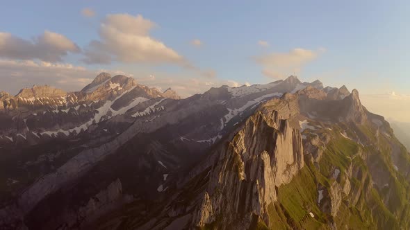 A drone flying around a mountain. It reveals a beautiful background with snow covering  the very top