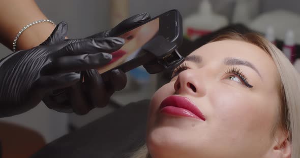 The Girl on a Mobile Phone Takes Pictures of the Client's Face in a Beauty Salon