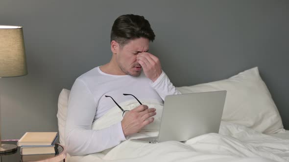 Stressed Middle Aged Man with Headache Sitting in Bed 