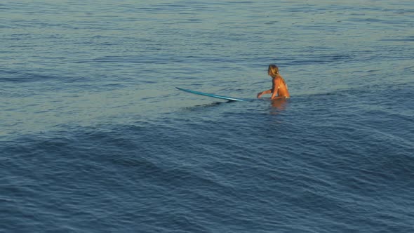 A young woman surfing in a bikini on a longboard surfboard.