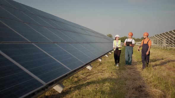 Business Team of Industrial Engineers Walking on Solar Farm and Discussing