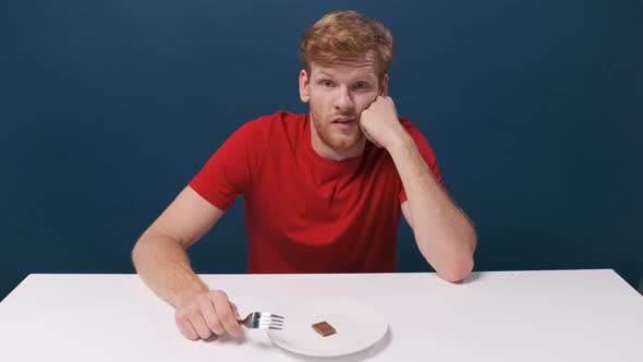 Funny Hungry Man Eats a Small Piece of Chocolate From a Halfempty Plate