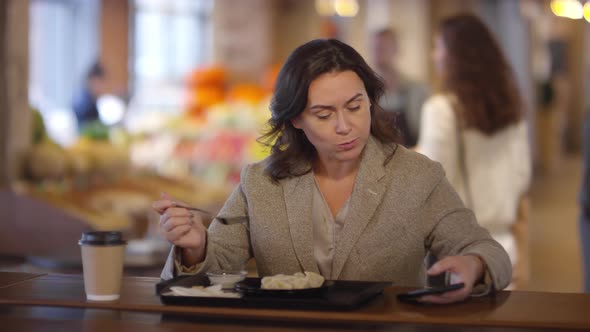 Woman Using Smartphone while Having Lunch in Food Market