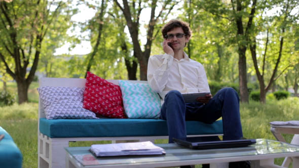 Young Businessman Working on Tablet and Speaks on the Phone