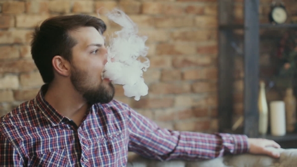 Man Exhaling Smoke From a Vaporizer. 
