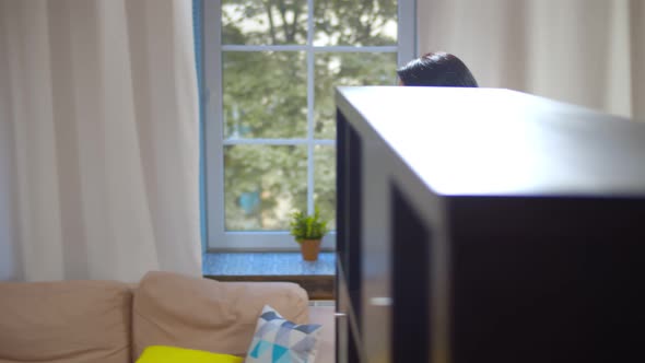 Young Woman Talking on Phone with Employer Looking After Baby Boy in Highchair at Home