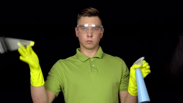 A Young Man Twists a Toilet Brush on Her Finger and Sprinkles Water From a Spray Bottle. Man in