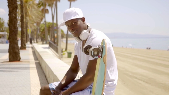 Handsome Young Black Man Seated On Beach Wall