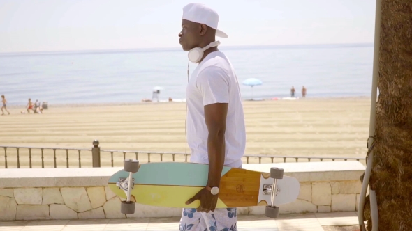 Young Skater Holding Board Near Sandy Beach