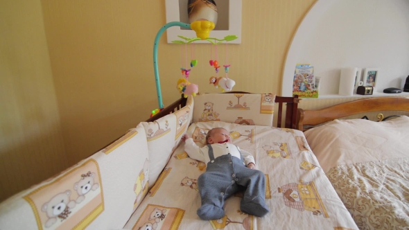 Little Cute Baby Boy Lying In Crib With Toy