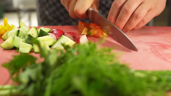 Male Chef's Hands Cut Tomato of Cutting Board.