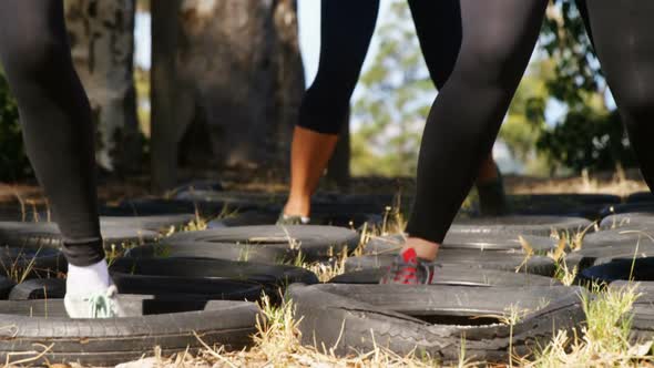 Low section of women running over tyres during obstacle course