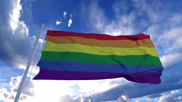Rainbow Flag Waving in the Wind Against Blue Sky
