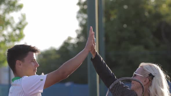 A Woman Trainer and Young Man Giving Each Other a High Five on the Tennis Court