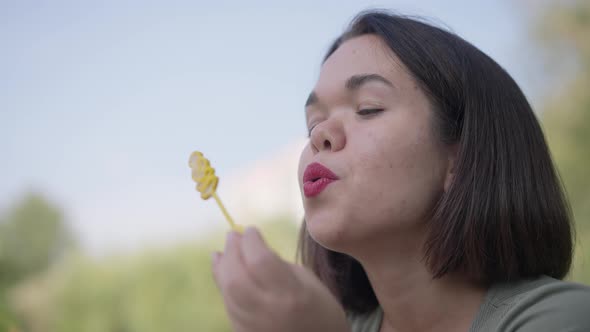 Headshot Portrait of Charming Positive Little Woman Blowing Soap Bubbles in Slow Motion Smiling