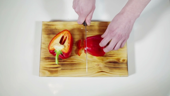 Man Slicing Red Bell Pepper On a Cutting Board 