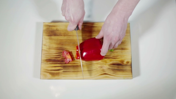 Man Slicing Red Bell Pepper On a Cutting Board 