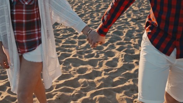 Young Couple Holding Hands At Sunset On Beach