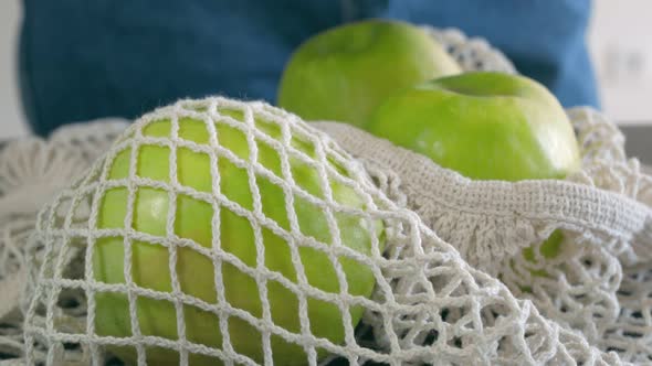 The Girl in Blue Jeans Takes One of the Four Apples with Her Right Hand and Places It on the Kitchen