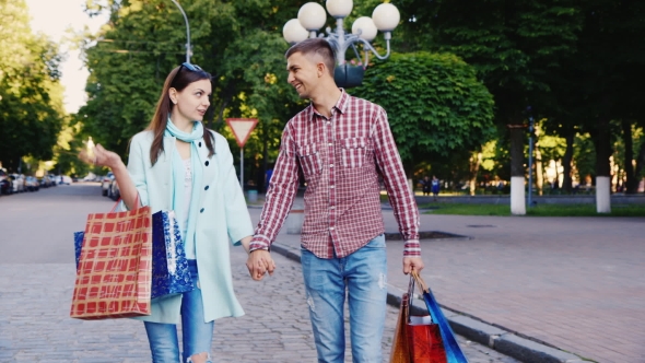 Young Couple Walking Through The City With Shopping Bags