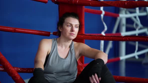 Female Boxer Sitting in Corner of Boxing Ring