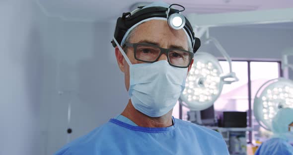 Close-up of Caucasian male doctor standing in surgical headlamp at operation theater in hospital