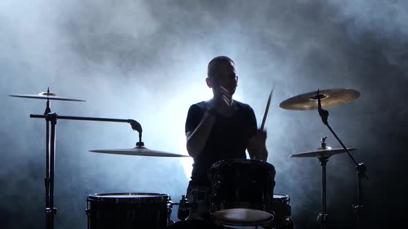 Professional Musician Plays Music on Drums with the Help of Sticks, Smoky Background, Silhouette