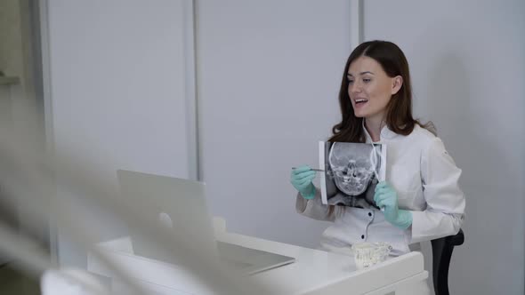 Dentist Conducts Online Consultation at Laptop Using Jaw Xray and Dental Tool
