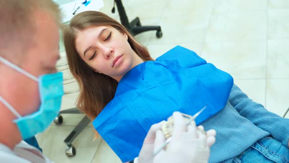 Beautiful young girl smiles and listens to the dentist