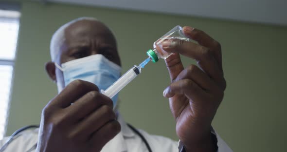 African american male doctor wearing face mask preparing injection