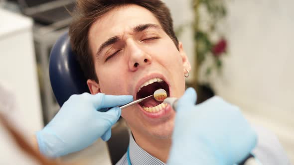 Dentist Using Dental Instruments to Check Teeth Sensitivity of Male Patient