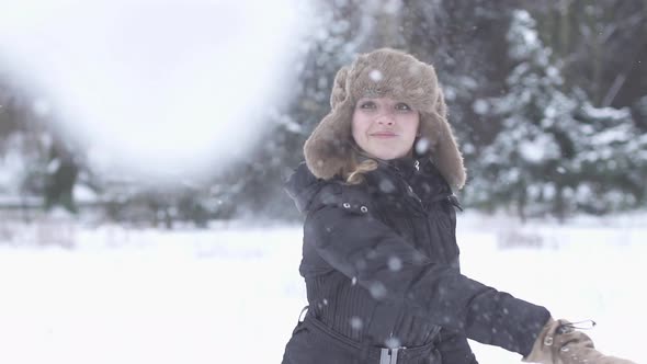 Happy Young Woman Throughing Snow Ball at Camera Having Fun