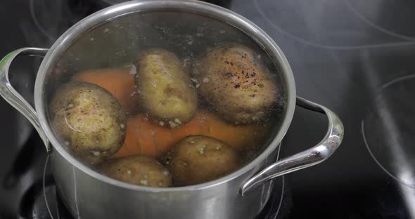 Hot Boiling Pan with Vegetables Potatoes and Carrots. Cooking in Kitchen