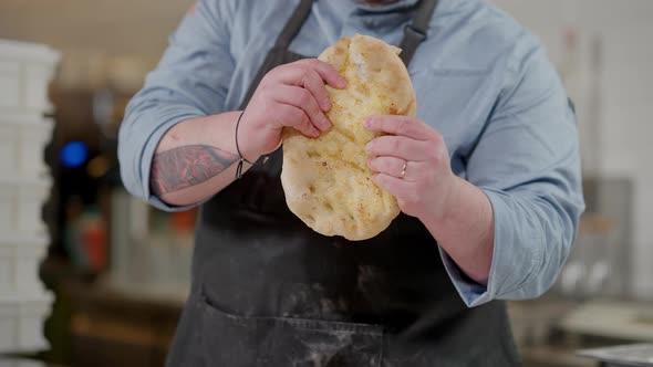 Camera Moves Up From Male Hands Breaking Dough to Face of Proud Professional Pizza Chef Smelling