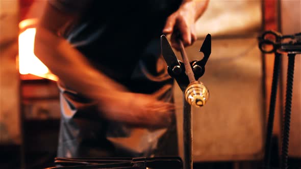 Mid section of glassblower shaping a molten glass