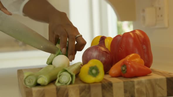 Mid-section of woman chopping vegetable in kitchen