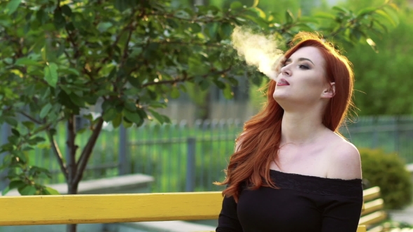 Passionate Woman Smoking In Black Dress, Sitting On a Bench