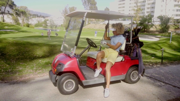Attractive Female Golfer Posing On a Red Golf Cart