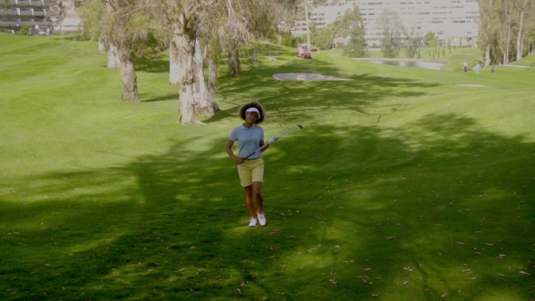 Young Female Golfer Walking Across The Golf Course